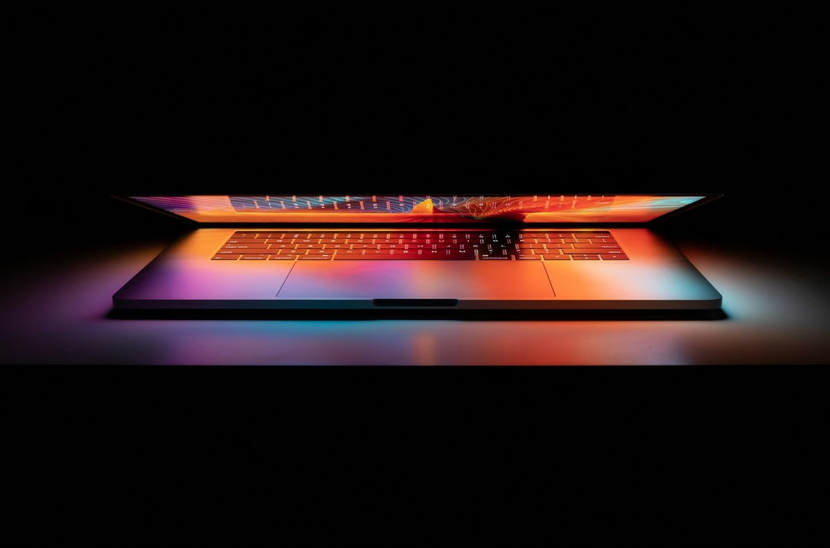 半開的 MacBook，螢幕彩色發光