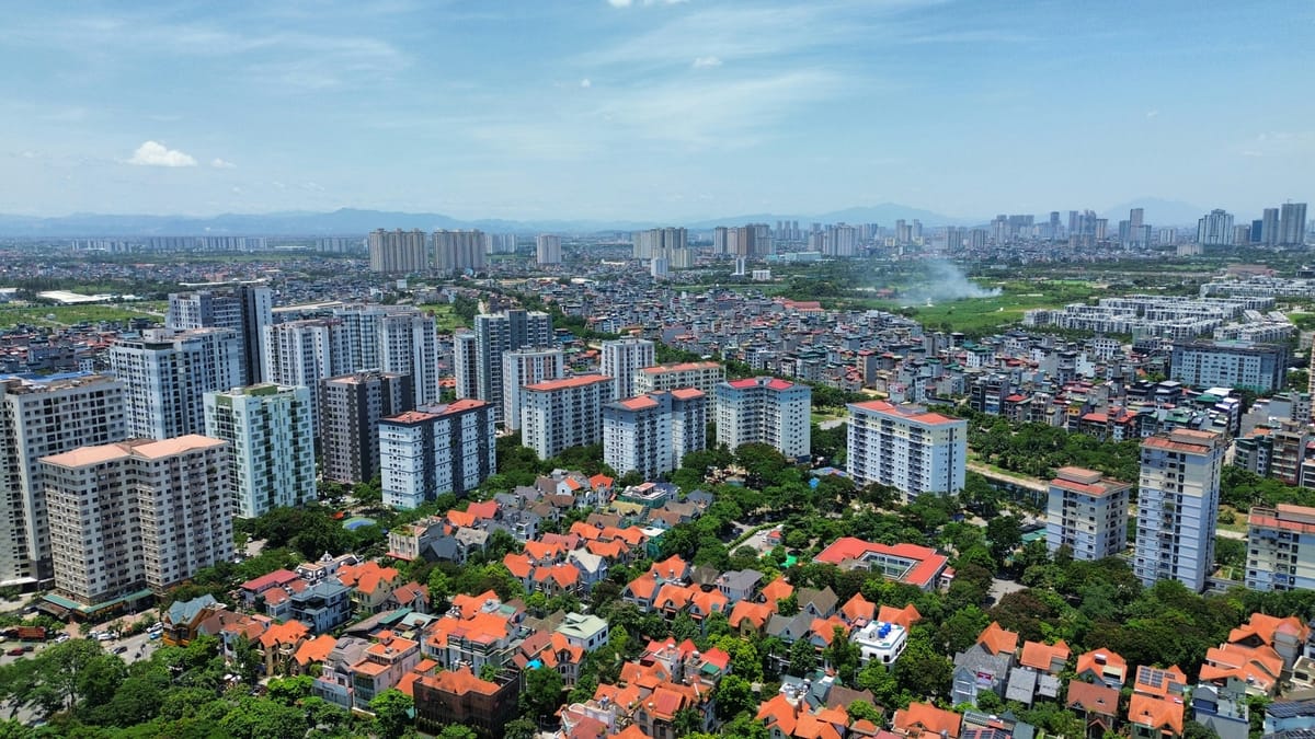 河內空拍：前景是橘瓦別墅群，中景一排公寓大樓，遠方是市區高樓天際線