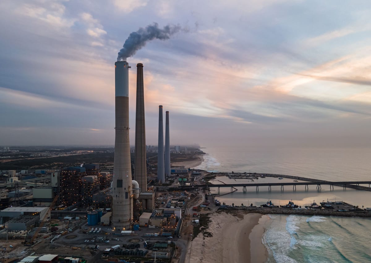黃昏時分的沿海燃煤電廠空拍，高聳煙囪冒著煙