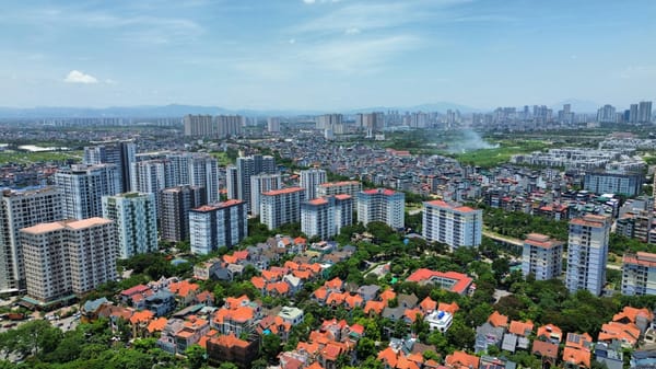 河內空拍：前景是橘瓦別墅群，中景一排公寓大樓，遠方是市區高樓天際線