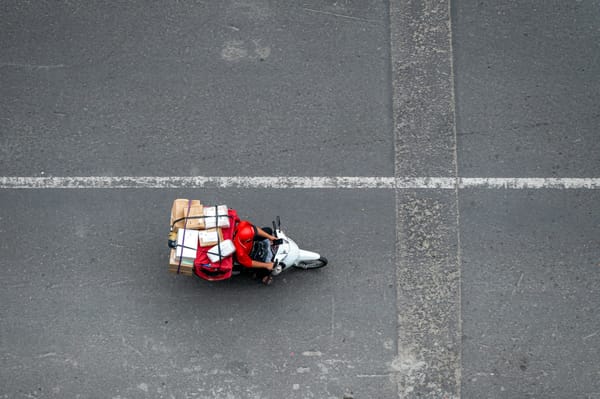 俯拍視角，快遞員騎機車載滿包裹獨自穿越馬路