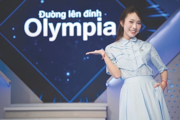 Khánh Vy 站在 Đường lên đỉnh Olympia 節目背板前主持
